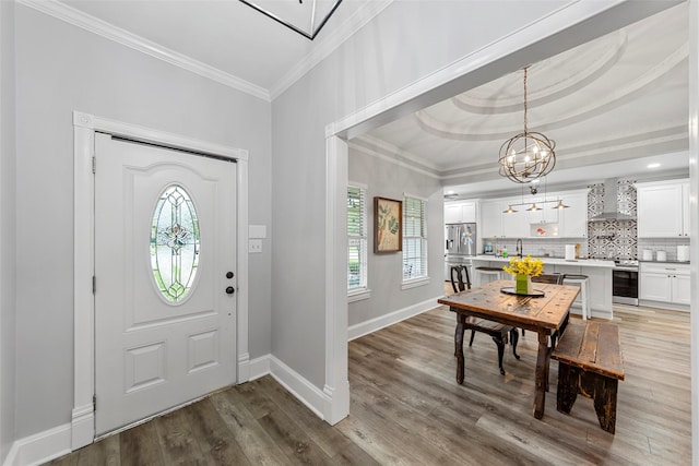 entryway with wine cooler, wood finished floors, crown molding, baseboards, and a notable chandelier
