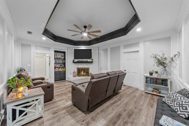 living area featuring crown molding, a ceiling fan, and a decorative wall