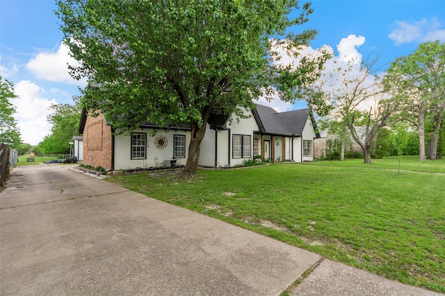 tudor home featuring brick siding, driveway, and a front yard