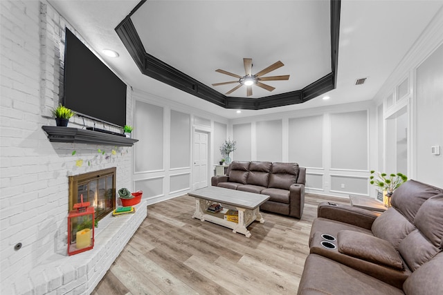 living room featuring wood finished floors, a decorative wall, crown molding, and ceiling fan