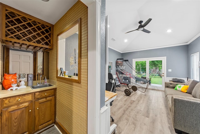 interior space with light wood finished floors, vaulted ceiling, a ceiling fan, ornamental molding, and a sink