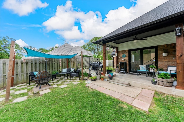 view of yard featuring a ceiling fan, a patio, an outdoor living space with a fire pit, and a fenced backyard