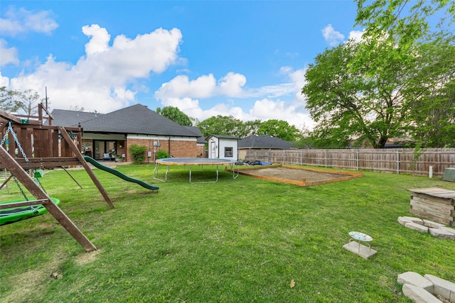 view of yard with a trampoline, a fenced backyard, an outdoor structure, and a playground