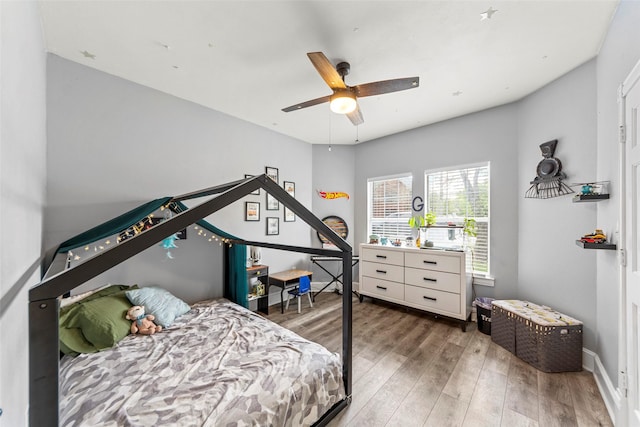 bedroom featuring ceiling fan, baseboards, and wood finished floors
