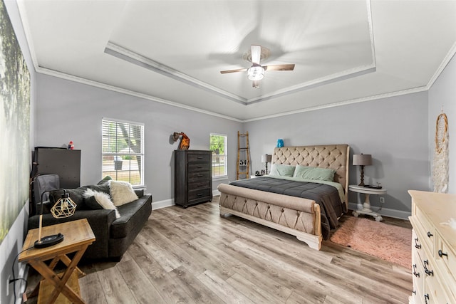 bedroom with ornamental molding, light wood-style floors, and a raised ceiling