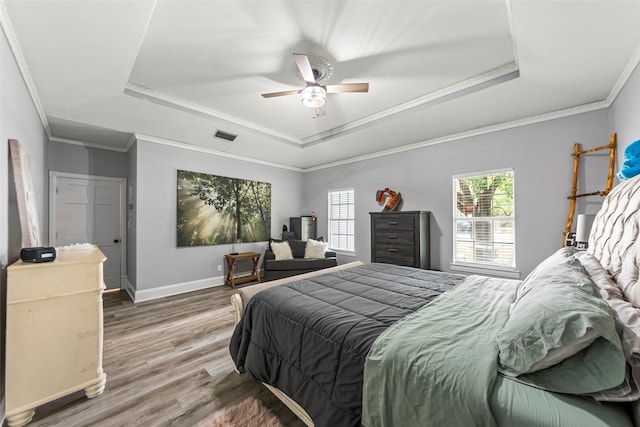 bedroom featuring crown molding, wood finished floors, ceiling fan, a raised ceiling, and baseboards