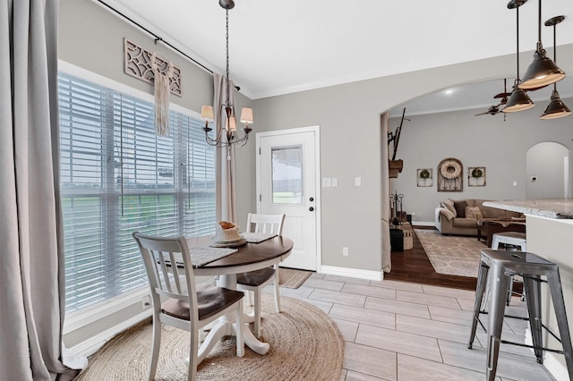 dining space with an inviting chandelier, arched walkways, crown molding, baseboards, and wood finish floors