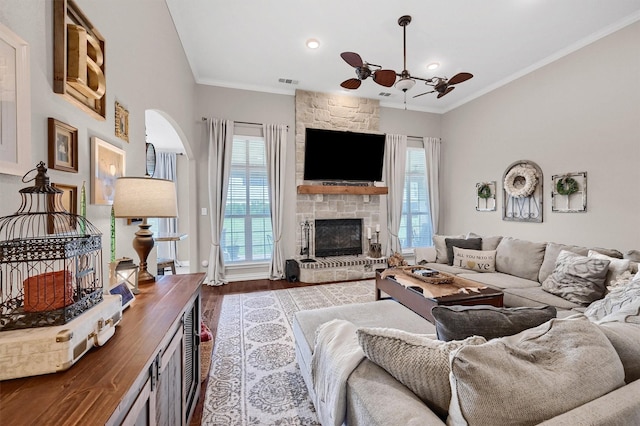 living room featuring a ceiling fan, wood finished floors, a fireplace, and ornamental molding