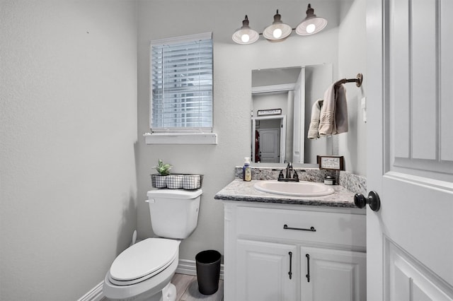 bathroom with baseboards, toilet, vanity, and wood finished floors