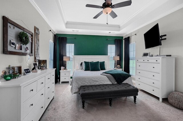 bedroom featuring light carpet, a tray ceiling, visible vents, a ceiling fan, and crown molding