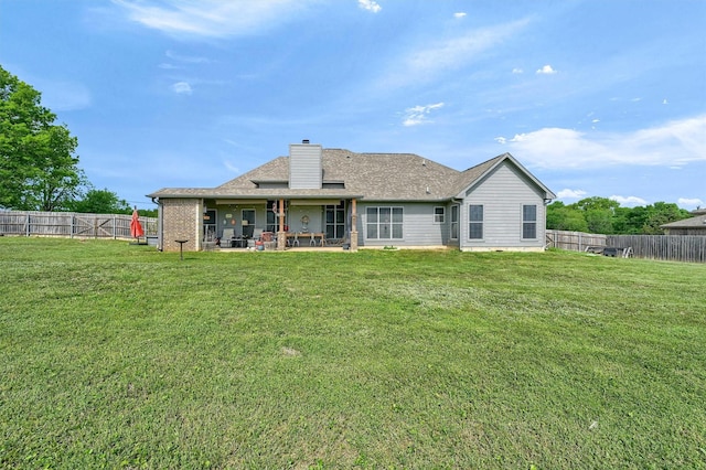 back of house featuring a yard, a patio area, a fenced backyard, and a chimney