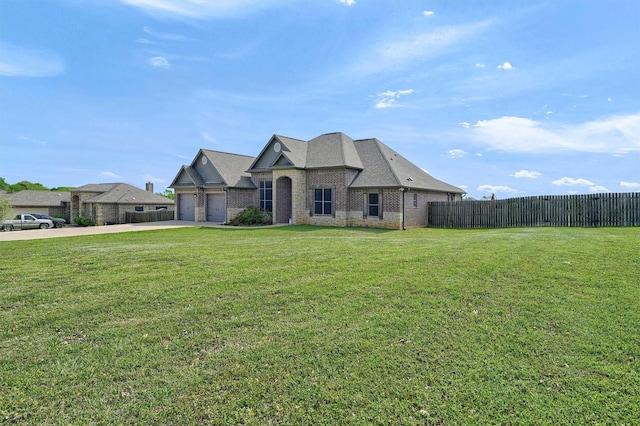 french country home with a garage, driveway, fence, a front yard, and brick siding