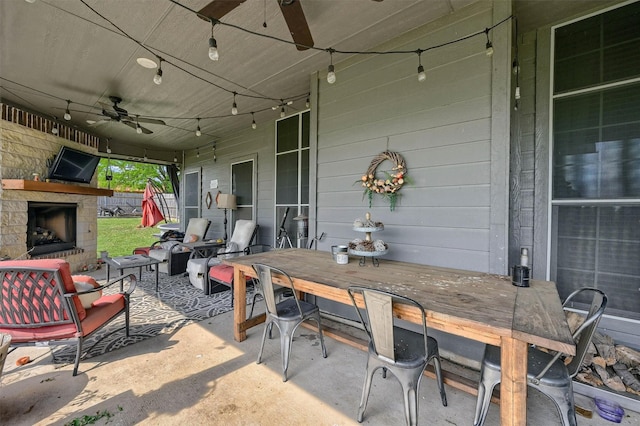 view of patio / terrace with outdoor dining area, an outdoor living space with a fireplace, and a ceiling fan