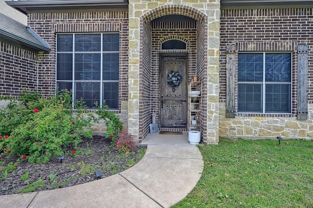 view of exterior entry featuring brick siding and stone siding