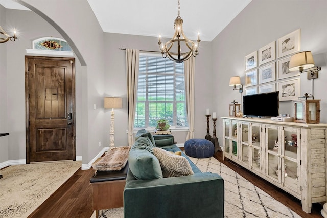 living area with a chandelier, arched walkways, baseboards, and wood finished floors