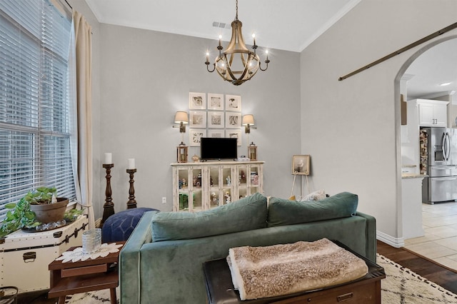 living room featuring wood finished floors, a chandelier, arched walkways, baseboards, and visible vents