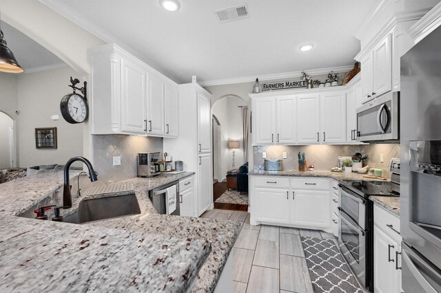 kitchen featuring arched walkways, appliances with stainless steel finishes, recessed lighting, and a sink
