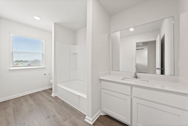 bathroom with  shower combination, toilet, baseboards, wood finished floors, and vanity