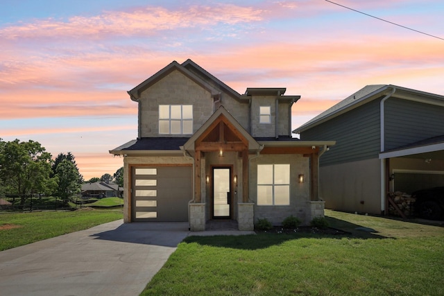modern home with a yard, an attached garage, driveway, and stone siding