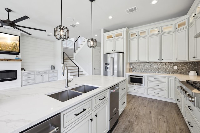 kitchen featuring white cabinets, a ceiling fan, a sink, hanging light fixtures, and appliances with stainless steel finishes