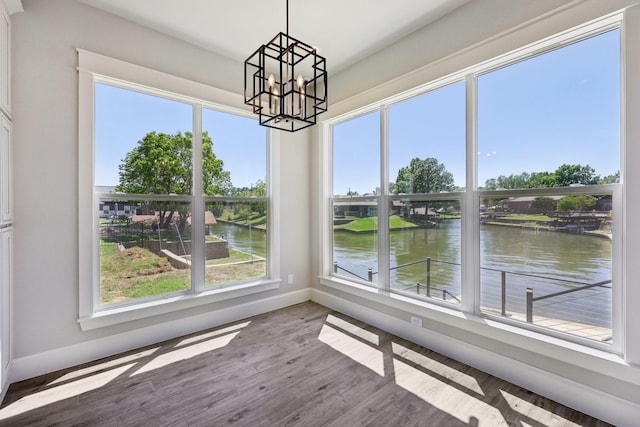 interior space with baseboards, an inviting chandelier, wood finished floors, and a water view