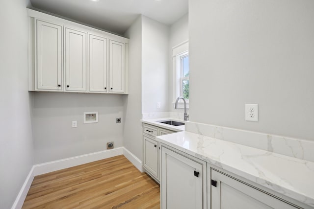 clothes washing area featuring light wood-style flooring, a sink, baseboards, hookup for a washing machine, and electric dryer hookup