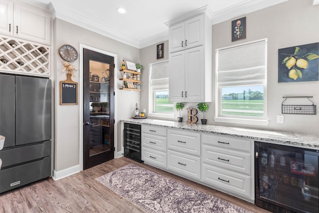 kitchen with white cabinetry, freestanding refrigerator, wine cooler, and light wood-style flooring