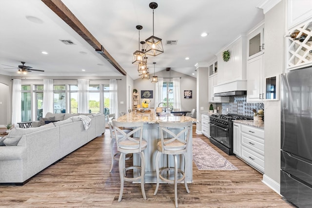 kitchen featuring visible vents, freestanding refrigerator, light stone countertops, double oven range, and open floor plan