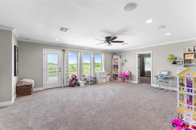 playroom featuring ceiling fan, ornamental molding, carpet flooring, and visible vents