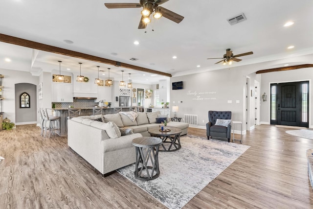 living room featuring arched walkways, visible vents, ceiling fan, and recessed lighting