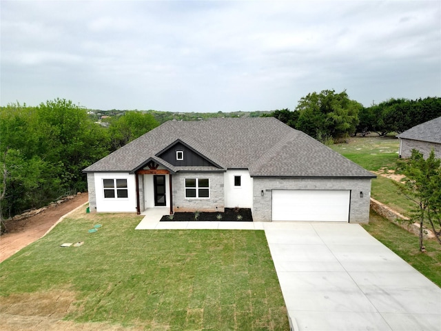 view of front of home with an attached garage, a shingled roof, a front yard, and concrete driveway