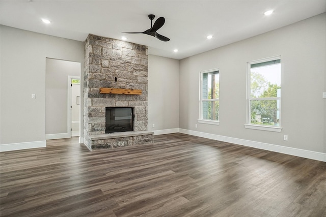 unfurnished living room featuring baseboards, a ceiling fan, dark wood-type flooring, and a fireplace