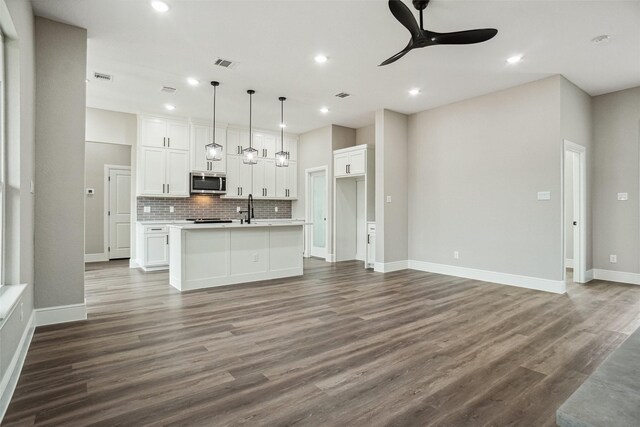 kitchen with white cabinets, decorative backsplash, ceiling fan, stainless steel microwave, and visible vents
