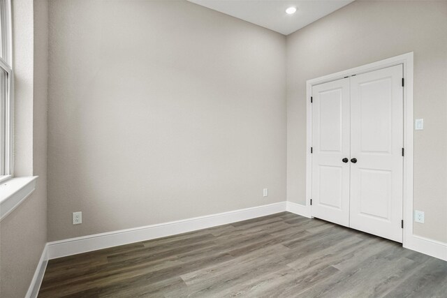 empty room with baseboards, wood finished floors, and recessed lighting