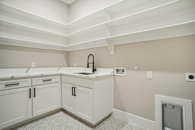 washroom with a sink, hookup for an electric dryer, cabinet space, baseboards, and washer hookup