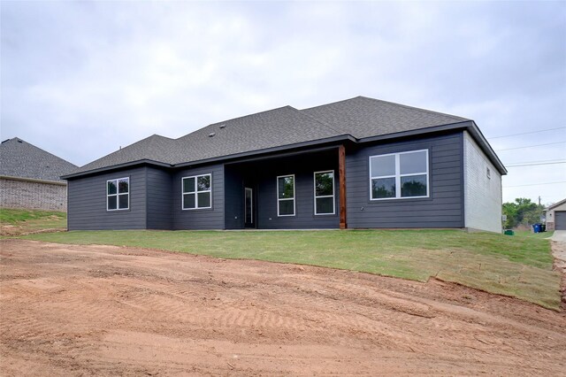 back of house with a lawn and a shingled roof