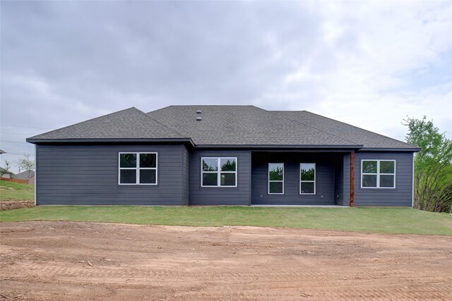 back of property featuring a yard and a shingled roof