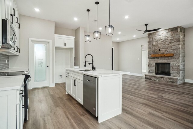 kitchen with a sink, open floor plan, wood finished floors, ceiling fan, and appliances with stainless steel finishes