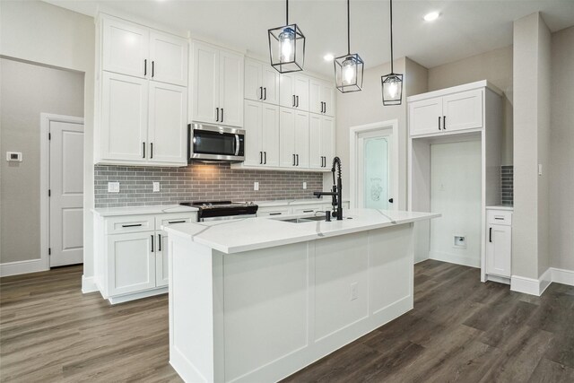 kitchen with stainless steel appliances, a sink, baseboards, decorative backsplash, and dark wood-type flooring