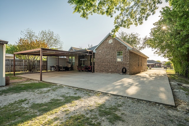 view of home's exterior featuring fence, gravel driveway, brick siding, and a carport