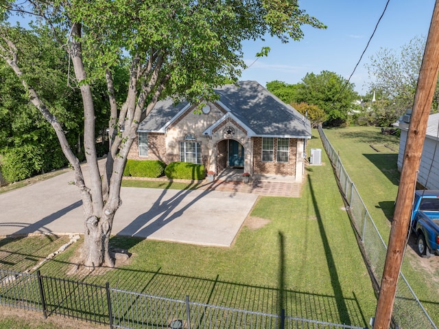 view of front facade featuring brick siding, a front yard, a shingled roof, and a fenced backyard