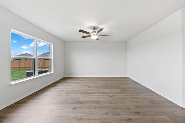 spare room with baseboards, a ceiling fan, and wood finished floors
