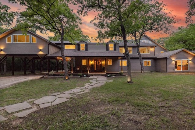 view of front of property featuring a porch, a lawn, driveway, and a carport