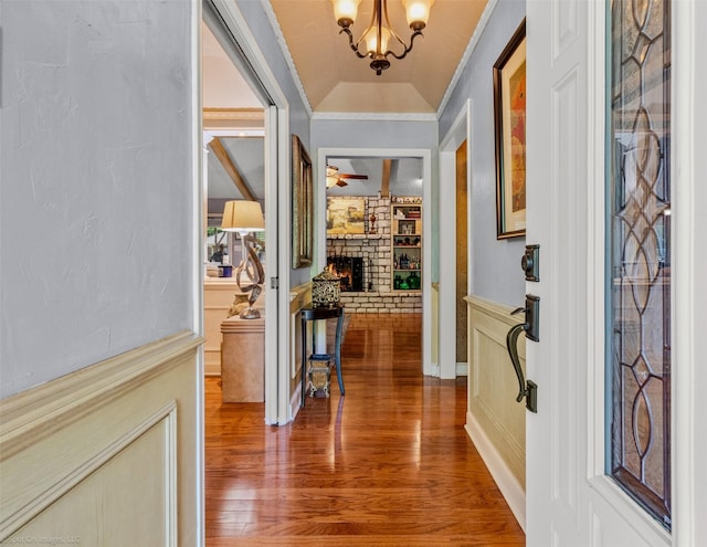 interior space with wood finished floors, a large fireplace, ornamental molding, and ceiling fan with notable chandelier