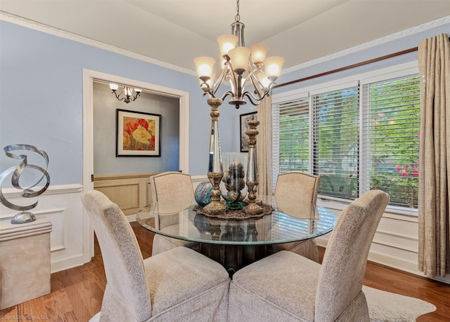 dining space with wood finished floors, a wainscoted wall, and a notable chandelier