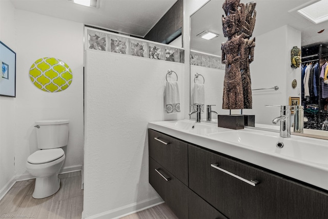 full bath with baseboards, wood finished floors, a sink, and toilet
