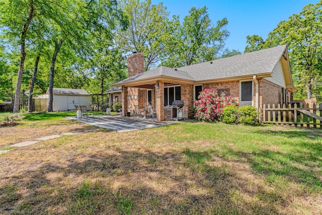 back of property featuring a chimney, fence, a yard, a patio, and brick siding