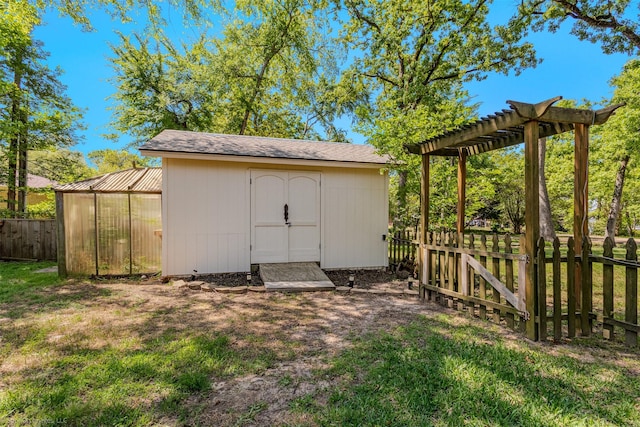 view of outbuilding featuring fence, a pergola, and an outdoor structure