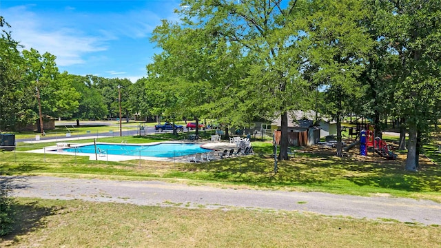 community pool featuring a lawn and playground community