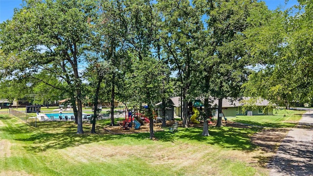 view of home's community with fence, playground community, and a yard